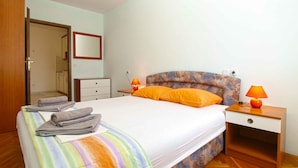 A bedroom with a bed, two bedside tables with lamps, a dresser, and a mirror.
