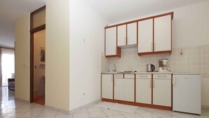 A kitchen with white cabinets, a sink, a coffee maker, and a refrigerator.
