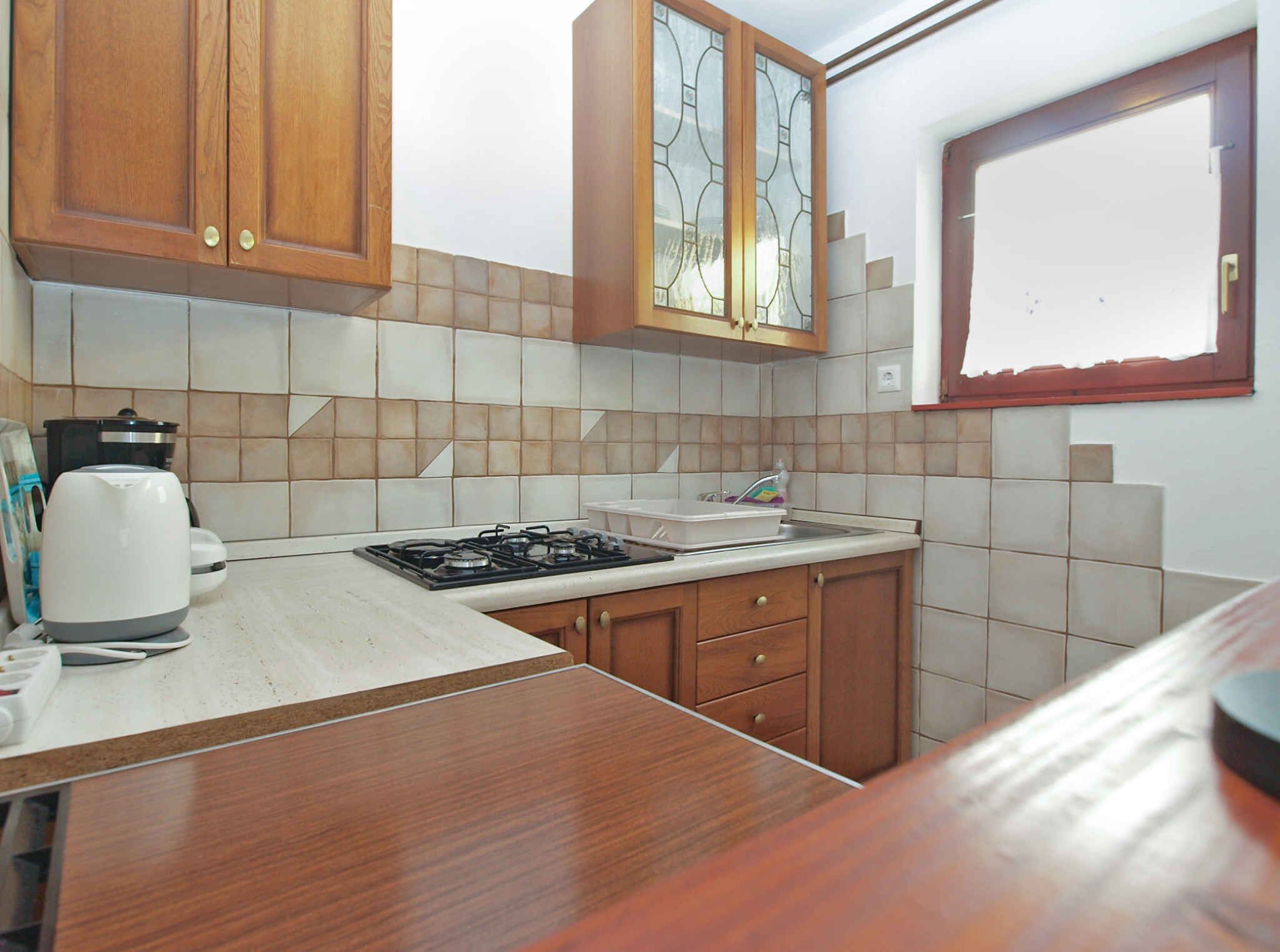 Una cocina compacta con armarios de madera, estufa a gas, un lavamanos y ventana con vistas.