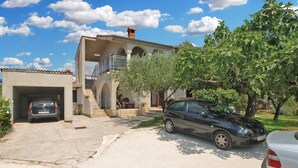 Un edifici de dues plantes amb garatge, escala i balcó.