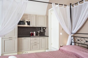 A bedroom with a bed, a nightstand, and a window with curtains.