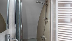 Een moderne badkamer met een douchecabine van glas, een handdouche en een toilet.
