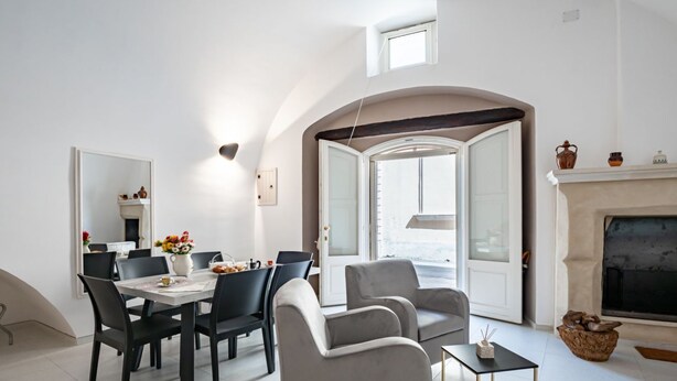 Een moderne woonkamer met een eethoek, een open haard en een groot raam.