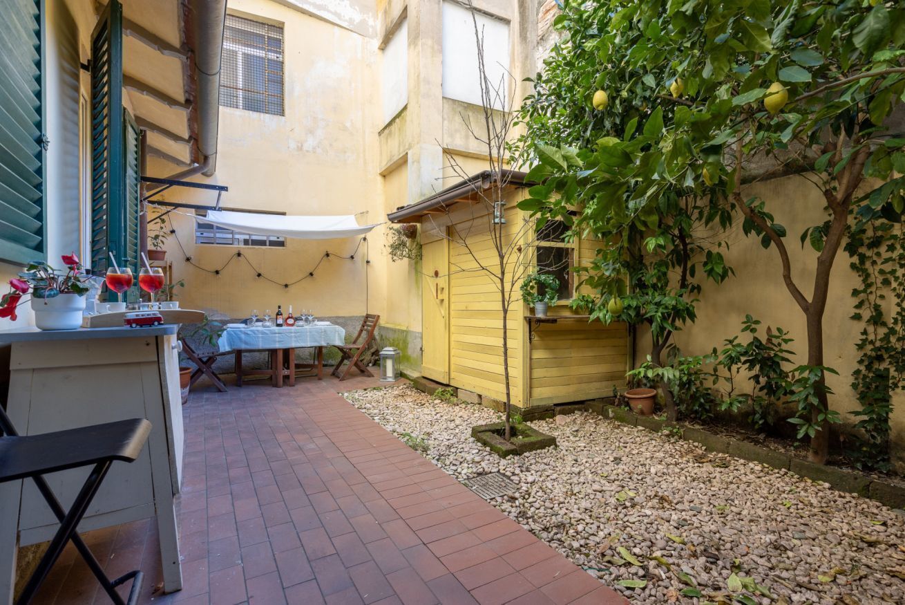 A courtyard with a table and chairs, a small shed, and a tree with fruit.