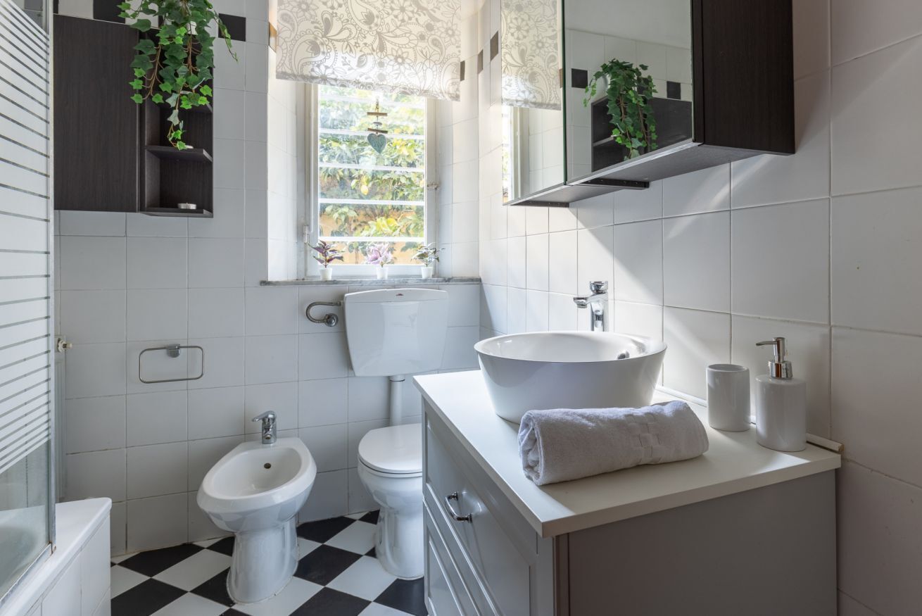 A bathroom with a bidet, toilet, sink, and mirror.