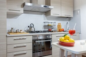 Una cocina moderna con electrodomésticos de acero inoxidable, armarios de madera y un frutero con limones.