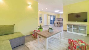 A living room with a sofa, a coffee table, a TV, and a dining area in the background. - Villa with swimming pool, terrace and barbecue (Peroj)