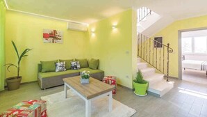 A living room with a sofa, a coffee table, a staircase, and a potted plant. - Villa with swimming pool, terrace and barbecue (Peroj)