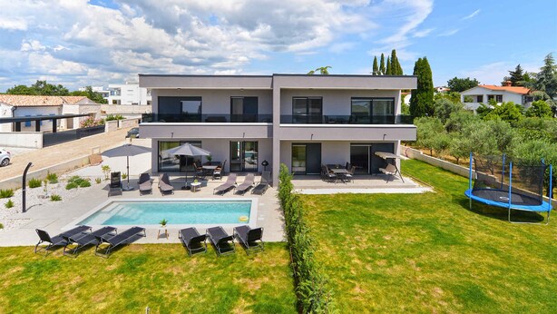 A modern two-story house with a swimming pool, outdoor seating, and a trampoline. - Modernly furnished villa with swimming pool (Peroj)