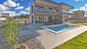 A modern two-story house with a swimming pool, outdoor seating, and a well-maintained garden. - Modernly furnished villa with swimming pool (Peroj)