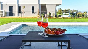 A table with two glasses of red wine and a plate of strawberries and chocolate croissants by a poolside. - Modernly furnished villa with swimming pool (Peroj)