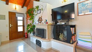 A living room with a fireplace, television, and a wooden ceiling. - Holiday apartment with air conditioning (Poreč)
