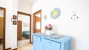 A room with a blue cabinet, a bed with a green bedspread, and a door leading to another room.