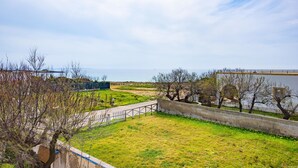 A grassy area with a pathway, a stone wall, and a view of the sea.