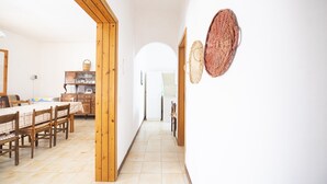 Een ruime hal met houten vloeren, een eethoek met tafel en stoelen, en twee gevlochten manden aan de muur.