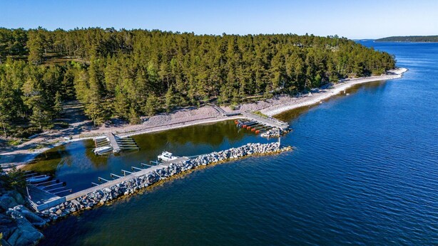 An aerial view of a coastal area with a dock, boats, and a forested peninsula. - Smultronstället by Interhome (Stavsnäs)