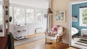 A spacious room with large windows, a wicker chair, a white radiator, and a wooden floor. - Smultronstället by Interhome (Stavsnäs)