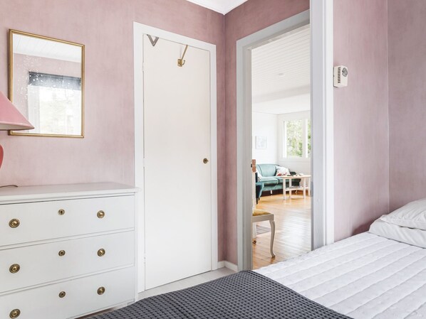 A bedroom with a bed, a dresser, a door, and a view of a living area. - Smultronstället by Interhome (Stavsnäs)