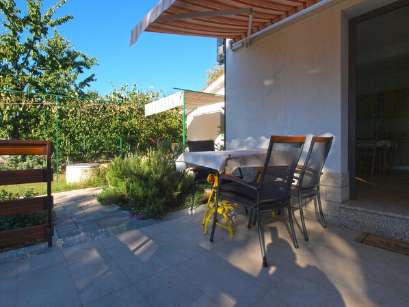An outdoor patio with a table and chairs, a covered area, and a view of a building.