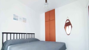 A bedroom with a bed, a wardrobe, and a small window. - Holiday apartment with balcony and air conditioning (Lido di Jesolo)