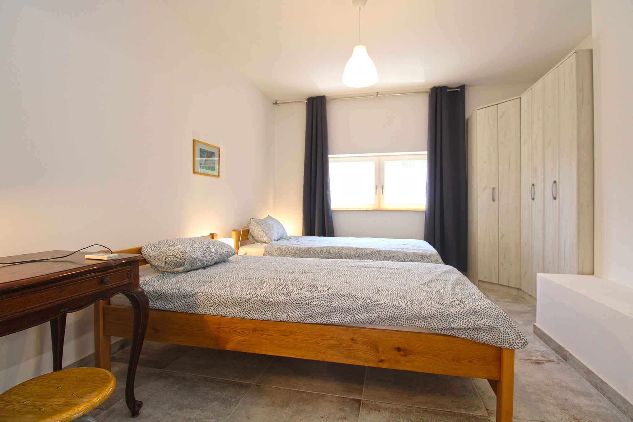 Une chambre avec deux lits, un bureau, une chaise et une armoire.
