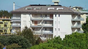 A multi-story residential building with balconies, a sign indicating 'Residence St. Nicholas', and a clear sky. - Studio only 100 m from the beach (Lido di Jesolo)