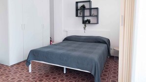 A bedroom with a bed, a wardrobe, and a wall-mounted shelf with plants. - Studio only 100 m from the beach (Lido di Jesolo)