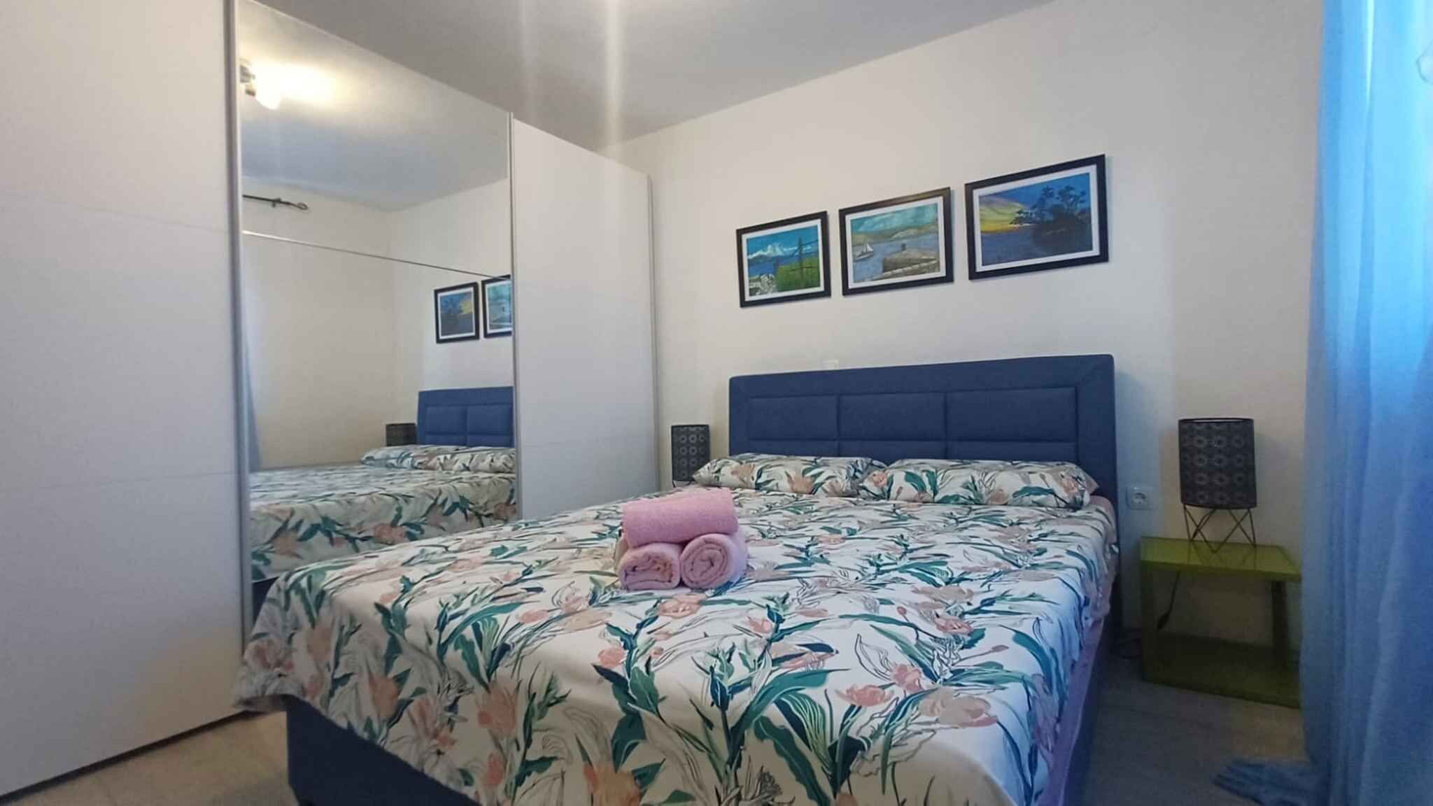 Une chambre à coucher avec un lit, un miroir et trois tableaux encadrés accrochés au mur.