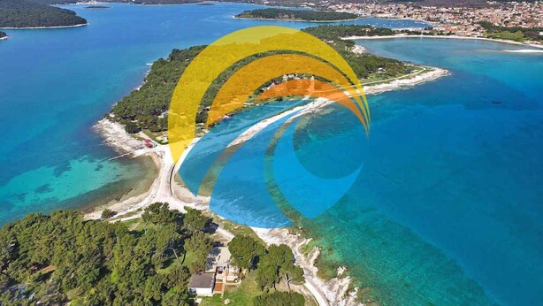 An aerial view of a coastal area with clear blue waters, a sandy beach, and a small island with buildings. - Holiday apartment with air conditioning (Medulin)