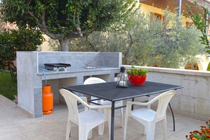 Enjoy al fresco dining in a serene garden setting with a grill and casual seating area.