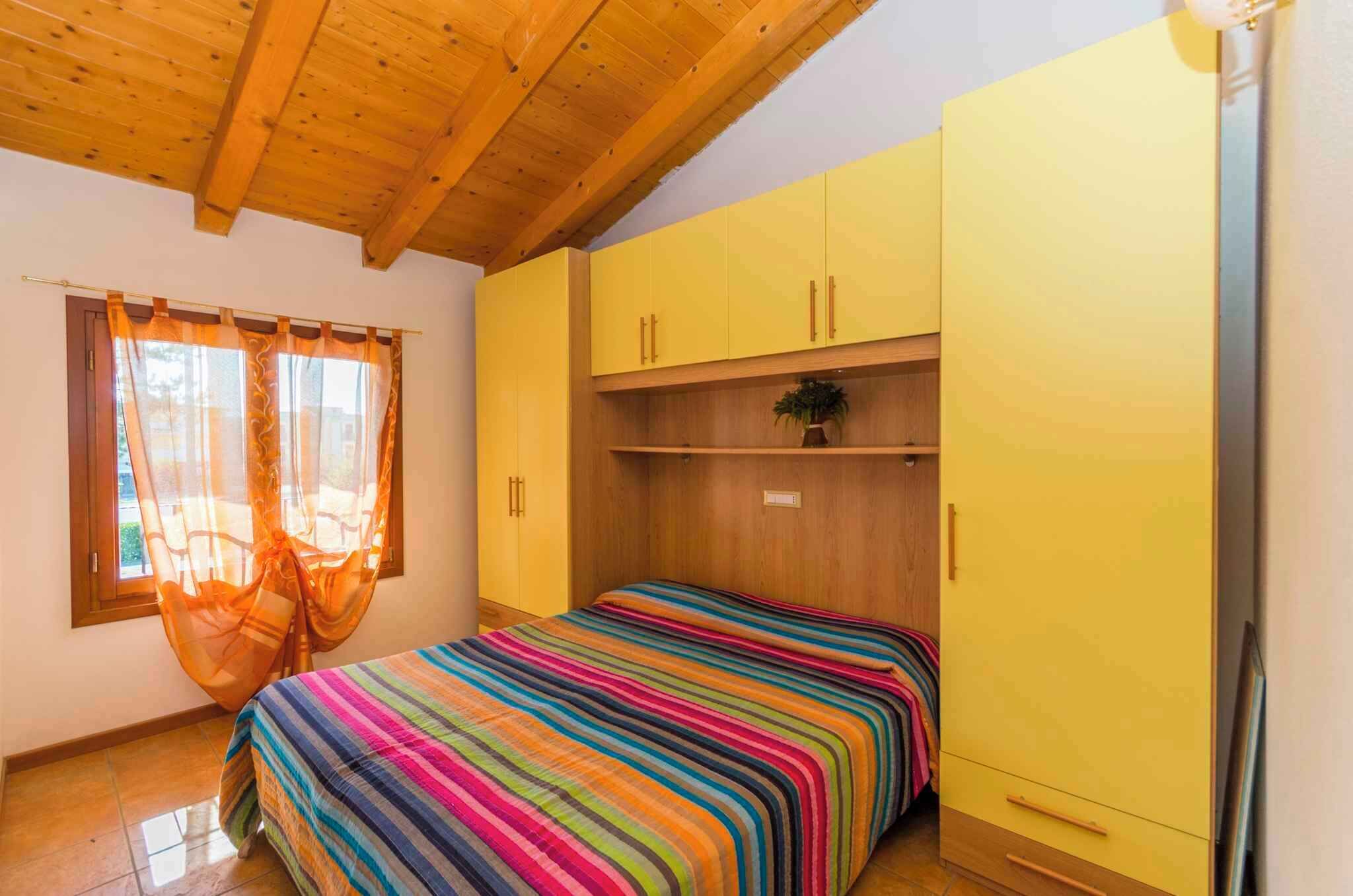 A bedroom with a bed, yellow wardrobe, and a window with curtains.