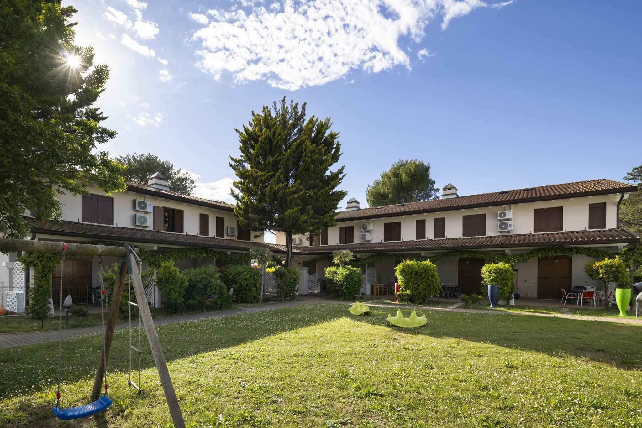 Un patio con un columpio, una pequeña fuente y un edificio con varias ventanas y unidades de aire acondicionado.