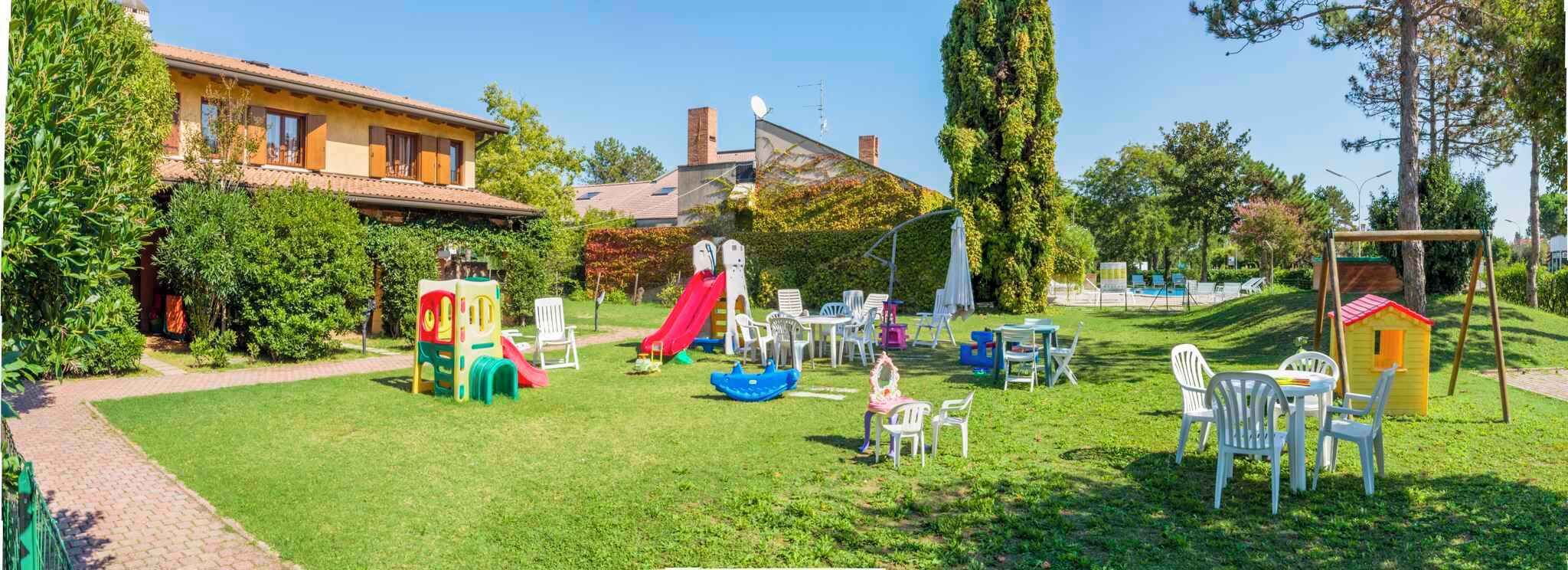 Un espace de jeux extérieur bien entretenu, équipé d’un toboggan, de structures de jeux et de sièges.