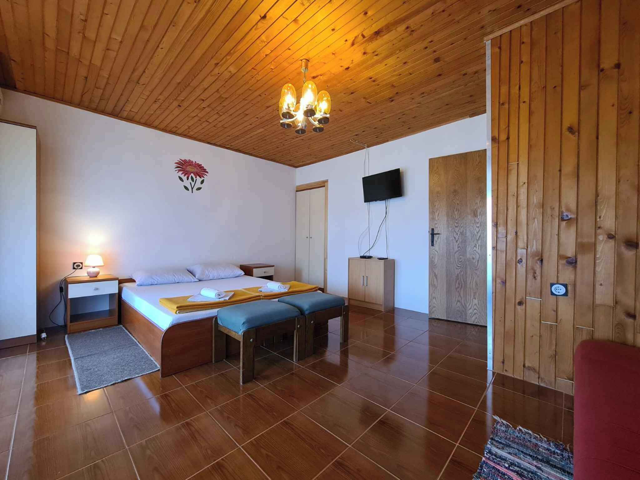 Un dormitorio con techo de madera, una cama con manta amarilla, un televisor y un armario.