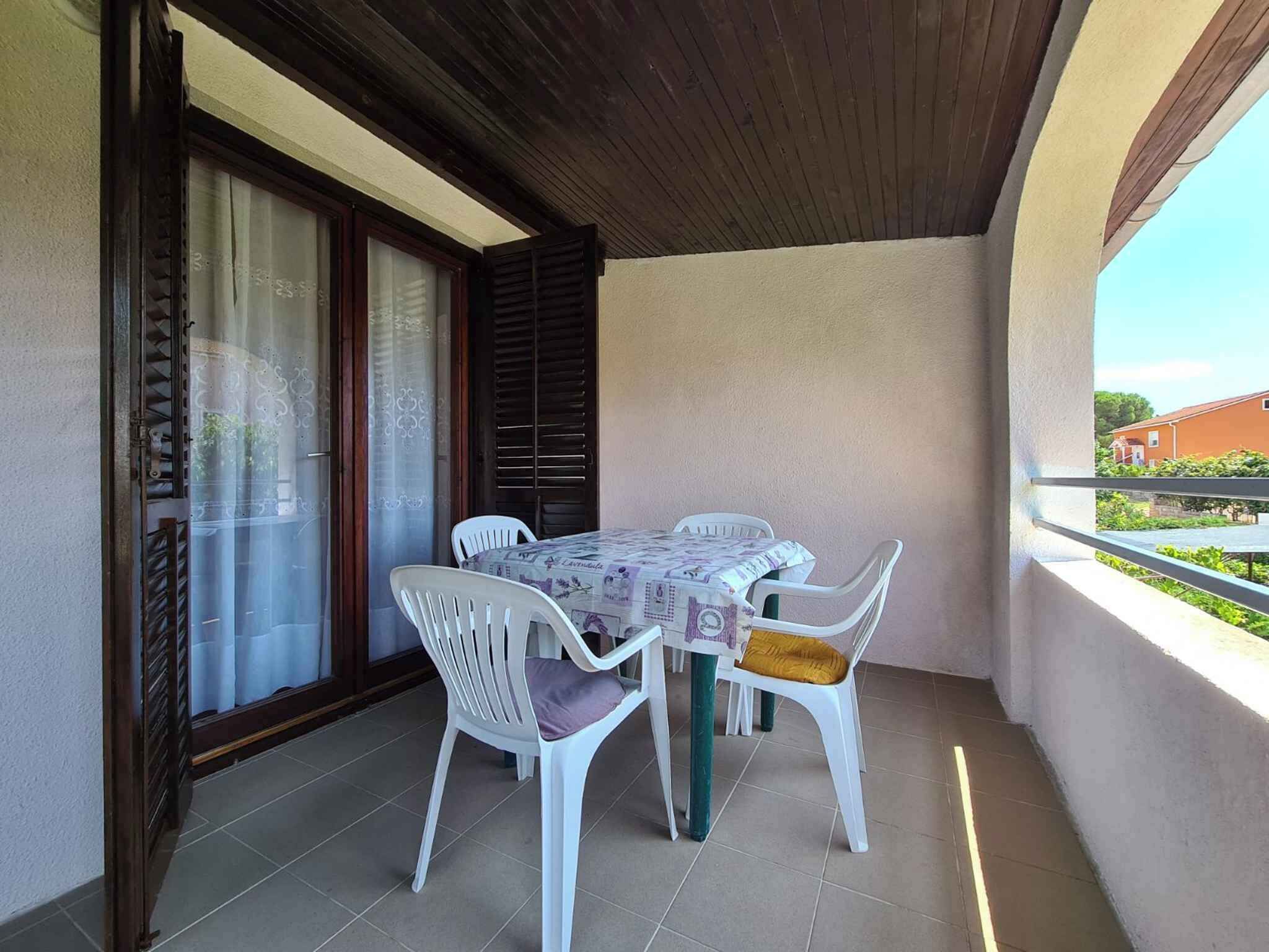 A balcony with a table and chairs, a sliding glass door, and a view of a building.