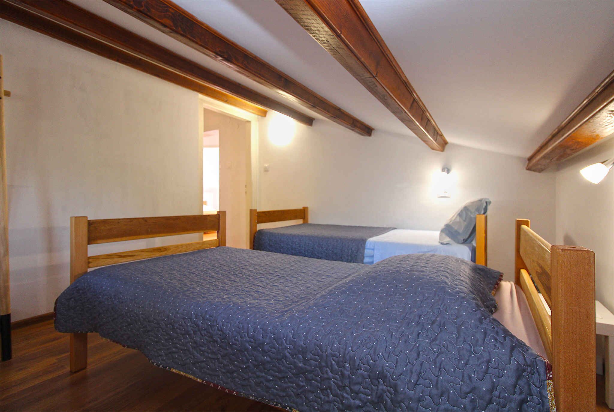 A bedroom with two wooden beds, a wooden ceiling, and a white wall.