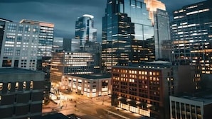 A cityscape at dusk with modern high-rise buildings, a central intersection, and illuminated windows. - Millenia Executive Apartment Guangzhou East Railway Station Zhujiang New Town Branch - Free Shuttle Bus to Canton Fair Complex During Canton Fair Period (Guangzhou)