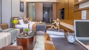 A modern hotel room with a bed, a sofa, a coffee table, a desk, a laptop, and a statue. - Millenia Executive Apartment Guangzhou East Railway Station Zhujiang New Town Branch - Free Shuttle Bus to Canton Fair Complex During Canton Fair Period (Guangzhou)