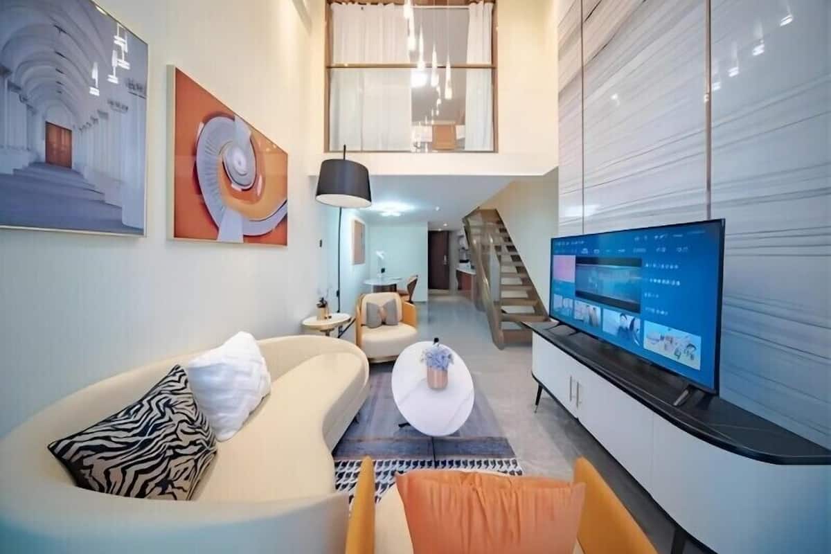 A modern living room with a sofa, a coffee table, a TV, and a staircase leading to an upper level.