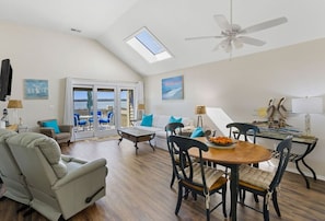 Un grand espace de vie comprenant une table à manger, des chaises, un canapé et un ventilateur de plafond.
