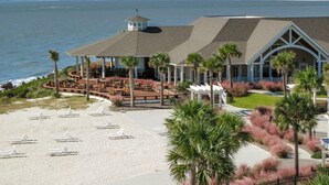Un hotel frente a la playa con zona de piscina, mobiliario exterior y vista al océano.