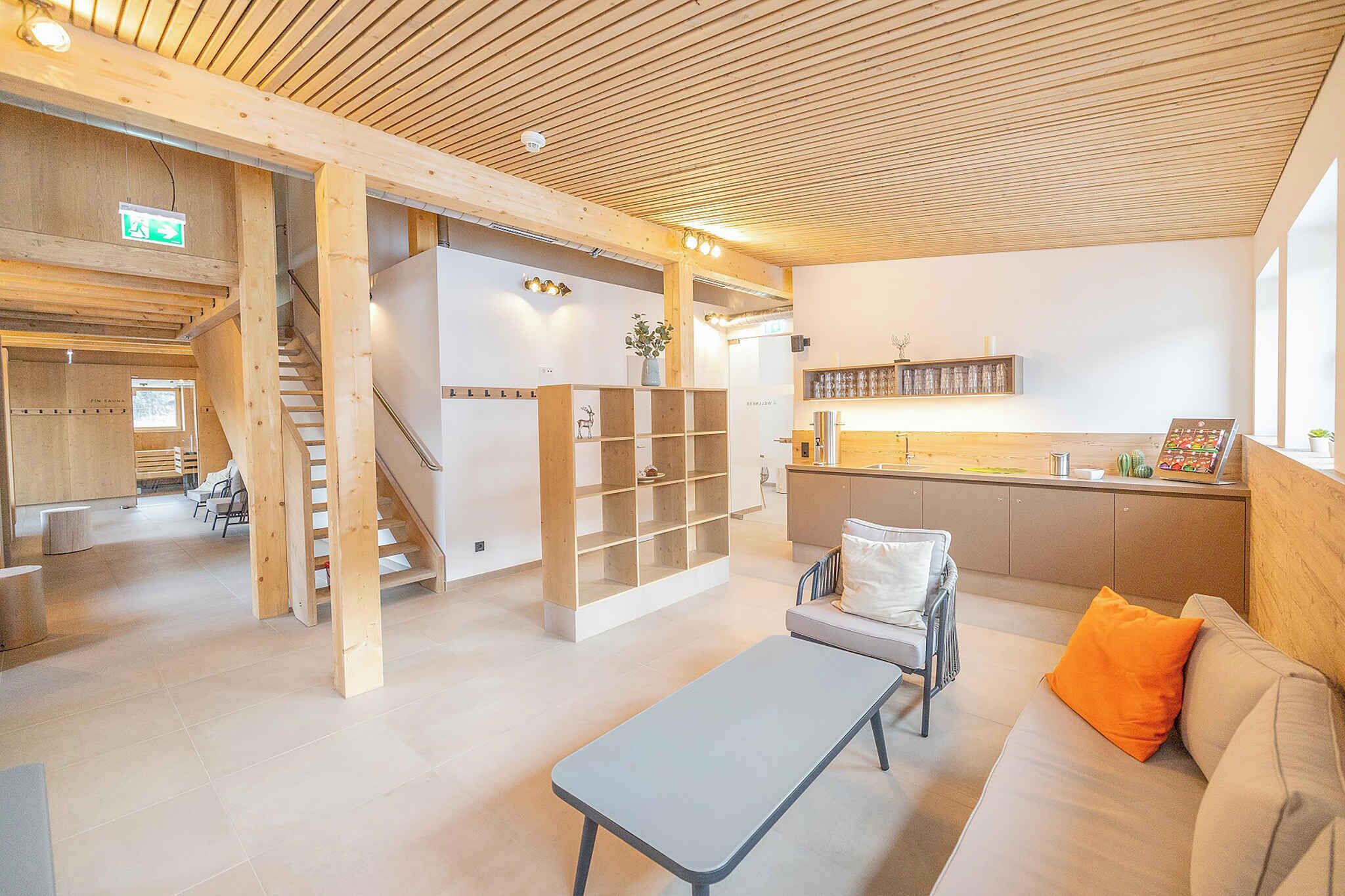 A modern interior with a wooden ceiling, a staircase, a seating area with a bench and cushions, and a kitchen counter with a display.