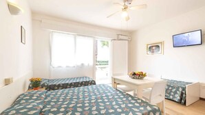 A room with two beds, a dining table, and a TV. - Holiday apartment with air conditioning (Lignano)