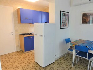 Compact kitchen area with a refrigerator, stove, and dining table.