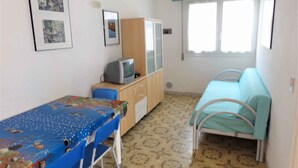 Une petite pièce simple, avec un lit, un bureau et un téléviseur.