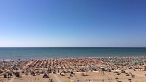 Une plage dotée de nombreux parasols et de chaises longues, ce qui indique la présence d’un grand complexe hôtelier en bord de mer.