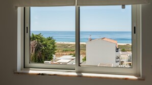 Ein Fenster mit Blick auf das Meer und Gebäude.
