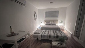 Une chambre à coucher comprenant un lit, des tables de chevet, un bureau et une chaise.