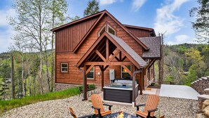 Una cabaña de madera con jacuzzi, zona de estar al aire libre y una chimenea.