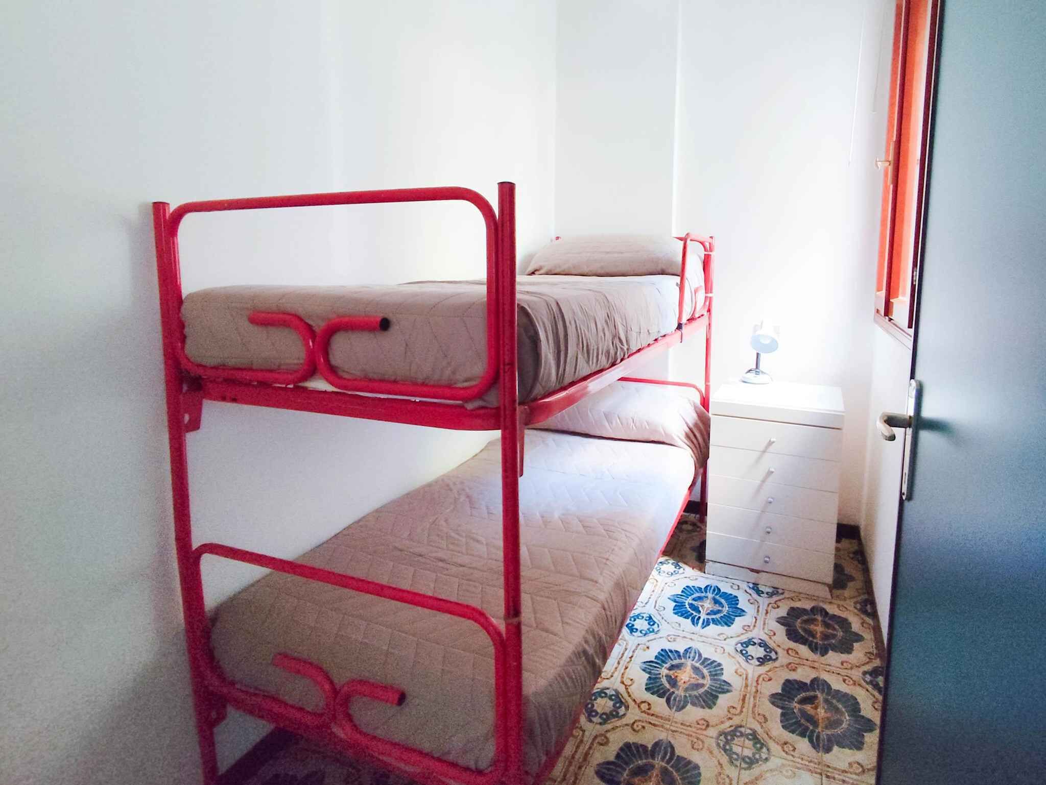 A bunk bed with a white drawer unit and a patterned floor.
